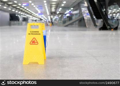 yellow plastic cone with sign showing warning of wet floor in restaurant in department store