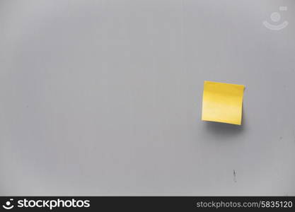 Yellow post-it note on a grey wall