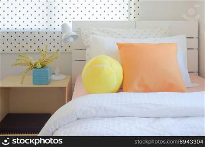 Yellow puffy ball and orange color pillow on bed in sweet color scheme bedroom