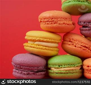 yellow, purple, green round baked macarons cakes on a red background, close up