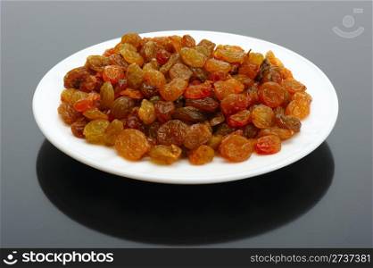 Yellow raisins on a white plate on a white background