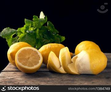 yellow ripe lemon and a bunch of fresh green mint on a wooden board, ingredients for lemonade
