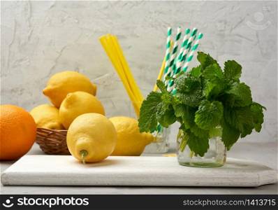 yellow ripe lemon and a bunch of fresh green mint on a wooden board, ingredients for lemonade