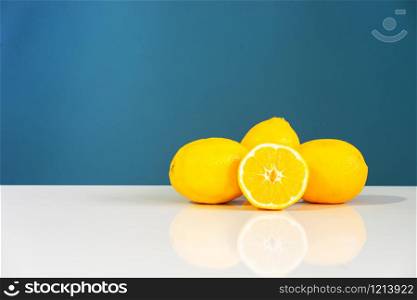 Yellow ripe lemon sliced in half juicy citrus fruit on the white table in front of the blue background wall fresh fruits