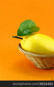 yellow ripe lemon with leaf over the orange background