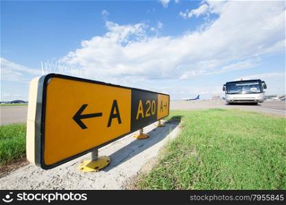 Yellow road sign in the airport, bus and airplane in the background