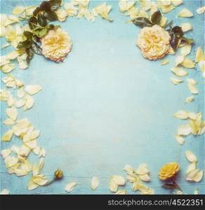 Yellow roses with petals on turquoise blue shabby chic background, top view, frame.