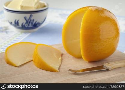 Yellow round Edam cheese with slices on a cutting board