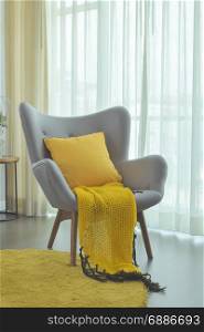 Yellow scarf and yellow pillow setting on gray color easy armchair in living room