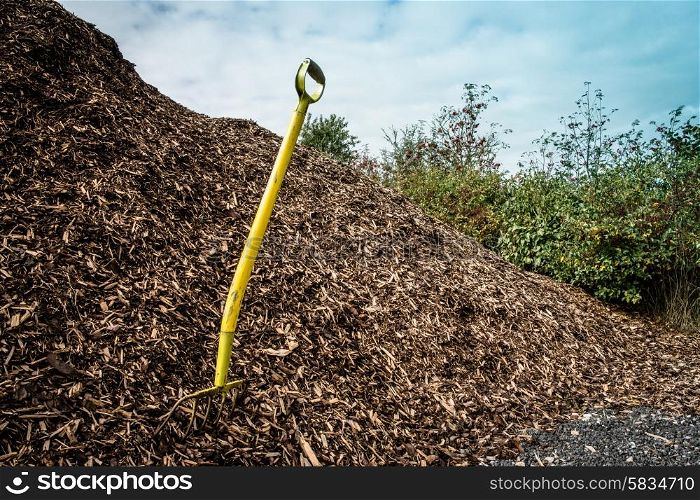 Yellow shovel in a big pile of mulch