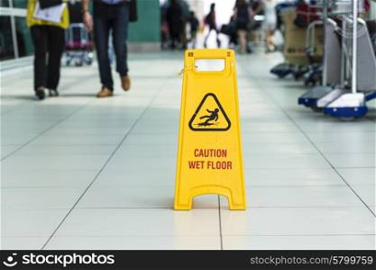 Yellow sign that alerts for wet floor in airport.