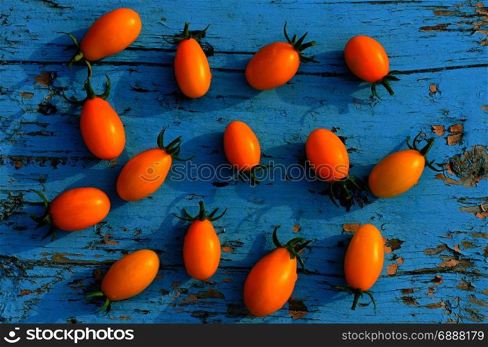 yellow small tomatoes on a blue wooden surface