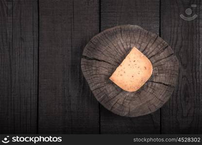 yellow smoked spicy cheese on a wooden end of a tree