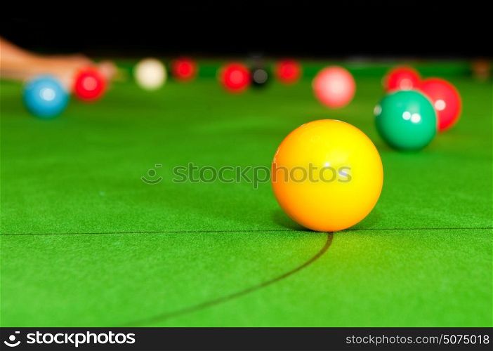 Yellow snooker ball on the table, with the game playing in the background. Selective focus-