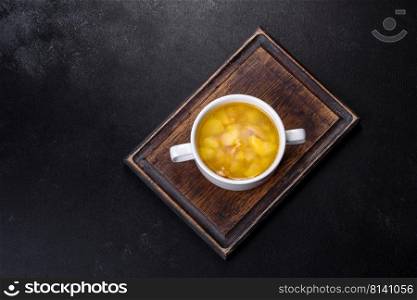 Yellow split pea soup with bacon. Space for text, top view. Fresh pea soup in bowl on black background. Cooking at home