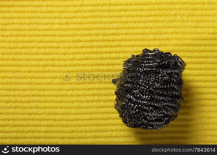 Yellow sponge background and stainless steel pan scourer