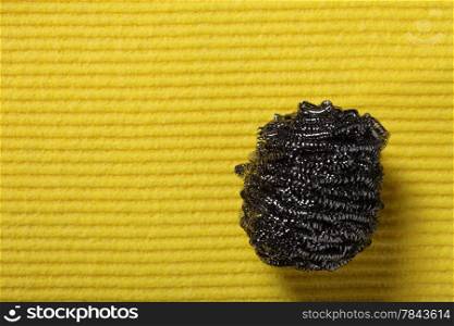 Yellow sponge background and stainless steel pan scourer