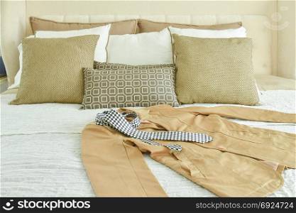 Yellow suit and tie setting on bed with brown and beige pillows
