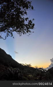 Yellow sunbeam over the blue sky with the silhouette of the mountain