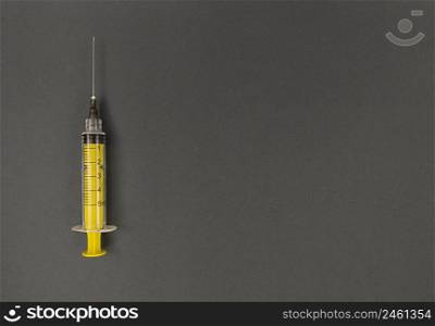 Yellow syringe on grey background. Simple flatlay with copy space.. Yellow syringe on grey background. Simple flat lay with copy space.