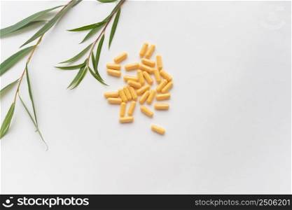 Yellow tablets of nutritional supplements lie on a white background. Place for an inscription. Green line in the background. Yellow tablets of nutritional supplements lie on a white background. Place for an inscription. Green line in the background.
