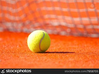 Yellow tennis ball on a orange court
