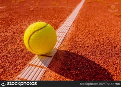 Yellow tennisball on the line at a clay court