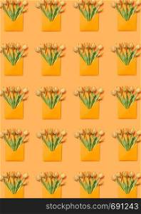 Yellow tulip bouquets in handcraft envelopes pattern on an orange background. Post card for congratulation. Flat lay.. Greeting envelopes pattern with tulip on a yellow background.