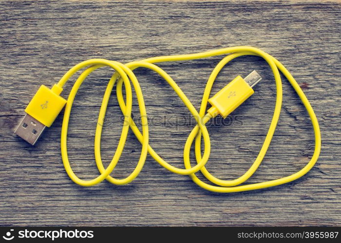 Yellow USB cable on wooden table - top view