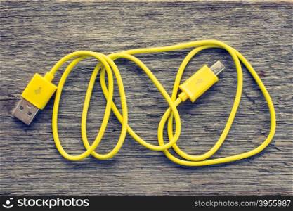 Yellow USB cable on wooden table - top view