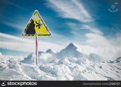 Yellow warning sign on the edge of the precipice, winter mountains and blue sky on background