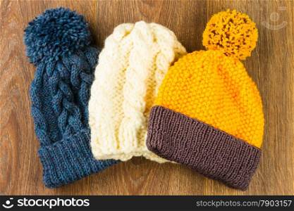 yellow, white and gray knitting caps on wooden background