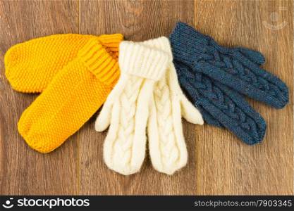 yellow, white and gray knitting mittens on wooden background