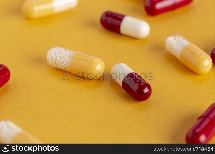 Yellow-white,red-white soluble capsules with medicine on a yellowbackground. Red-white, yellow-white soluble capsules with medicine on a colored background