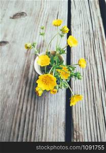 Yellow wild summer flowers in blue ceramic vase, on wooden veranda background. Still life in rustic style. Close up view. Spring in garden, countryside lifestyle concept. Copy space