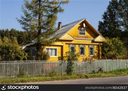 Yellow wooden house with decorated windows in russian village, Yaroslavl region. Autumn sunny day
