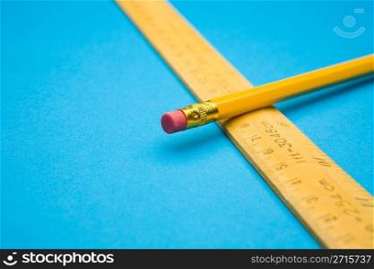 Yellow wooden ruler and pencil on blue background
