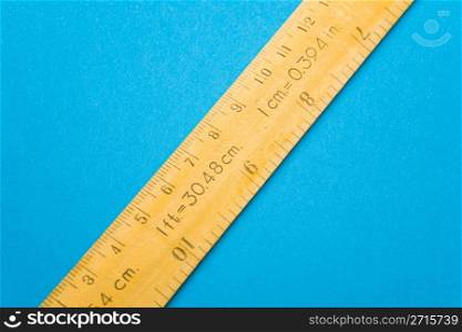 Yellow wooden ruler on blue background