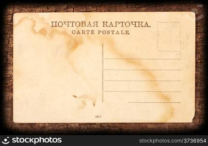 Yellowed postcard on the rough wooden background