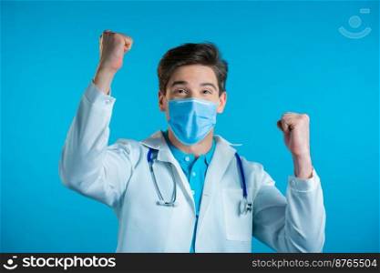 Yes winner gesture. Amazed doctor in white professional coat shocked. Handsome man surprised to camera over blue background. High quality photo. Yes winner gesture. Amazed doctor in white professional coat shocked. Handsome man surprised to camera over blue background