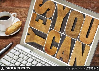 Yes you can - motivational slogan - a text in vintage letterpress wood type printing block on a laptop screen with a cup of coffee