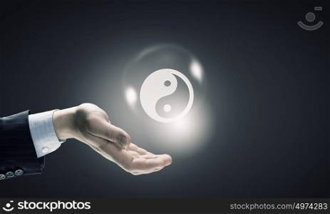 Yin yang philosophy. Close up of businessman holding yin yang symbols in palm