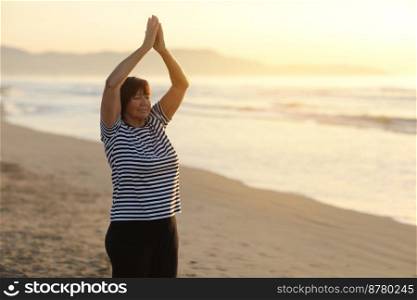 Yoga and meditation of mature woman practicing breath exercises on the sea beach on sunrise in the morning. Body mind and spirit, mindfulness concept. Enlightenment and healthy lifestyle. Yoga and meditation of mature woman practicing breath exercises on the sea beach on sunrise in the morning. Body mind and spirit, mindfulness concept. Enlightenment and healthy lifestyle.