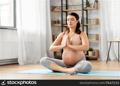 yoga and people concept - happy pregnant woman meditating at home. happy pregnant woman meditating at home