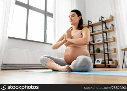 yoga and people concept - happy pregnant woman meditating at home. happy pregnant woman meditating at home