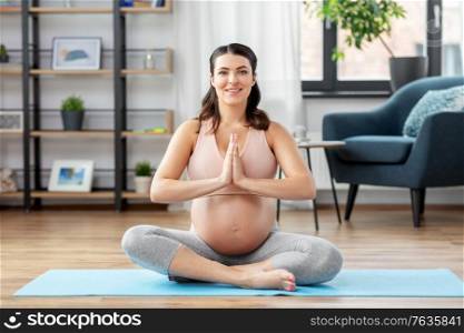 yoga and people concept - happy pregnant woman meditating at home. pregnant woman meditating at home