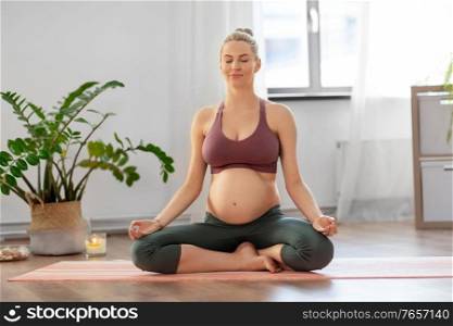 yoga and people concept - happy pregnant woman meditating at home. pregnant woman meditating at home