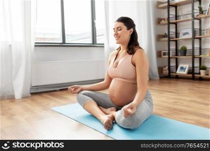 yoga and people concept - happy smiling pregnant woman meditating at home. happy smiling pregnant woman meditating at home