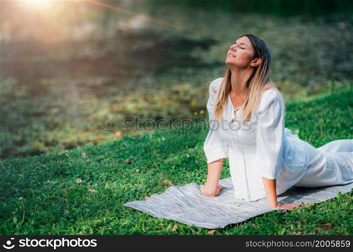 Yoga by the lake, cobra position, soft green background. Yoga by the lake, cobra position