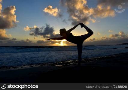 Yoga dancer pose silhouetted on the coast of Aruba.